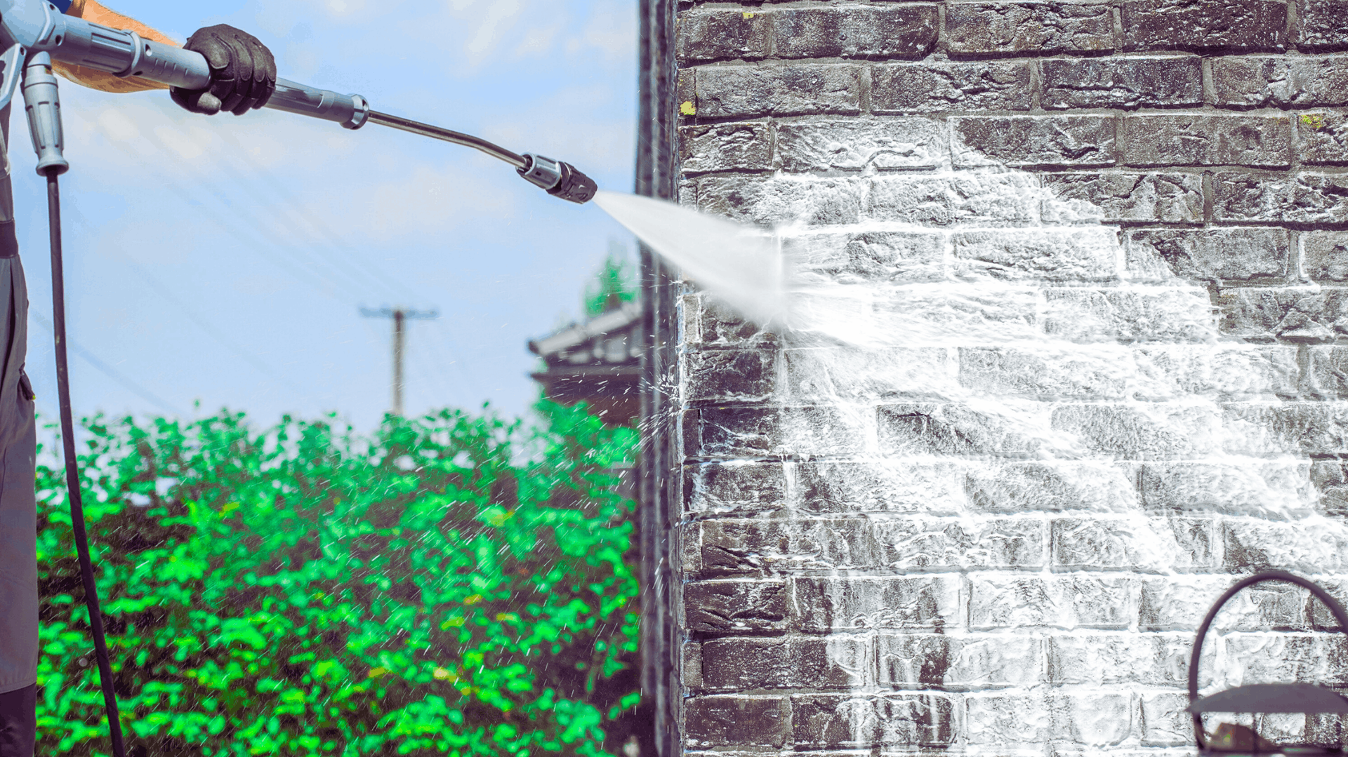 Person power washing a brick wall, cleaning the grime — Rohan's Maintenance in Robina, QLD