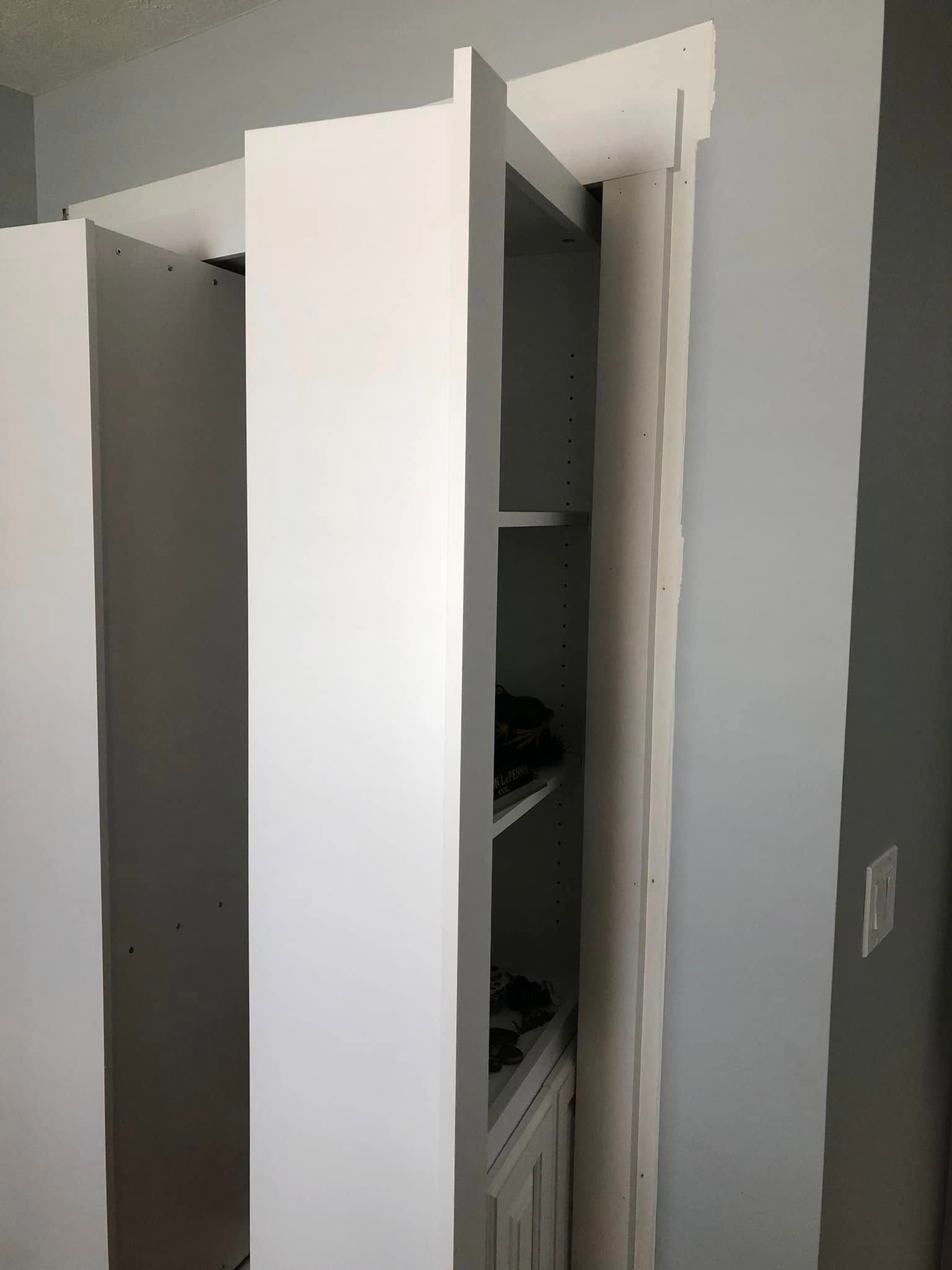 Open white closet door revealing shelves and stored items inside a narrow closet.