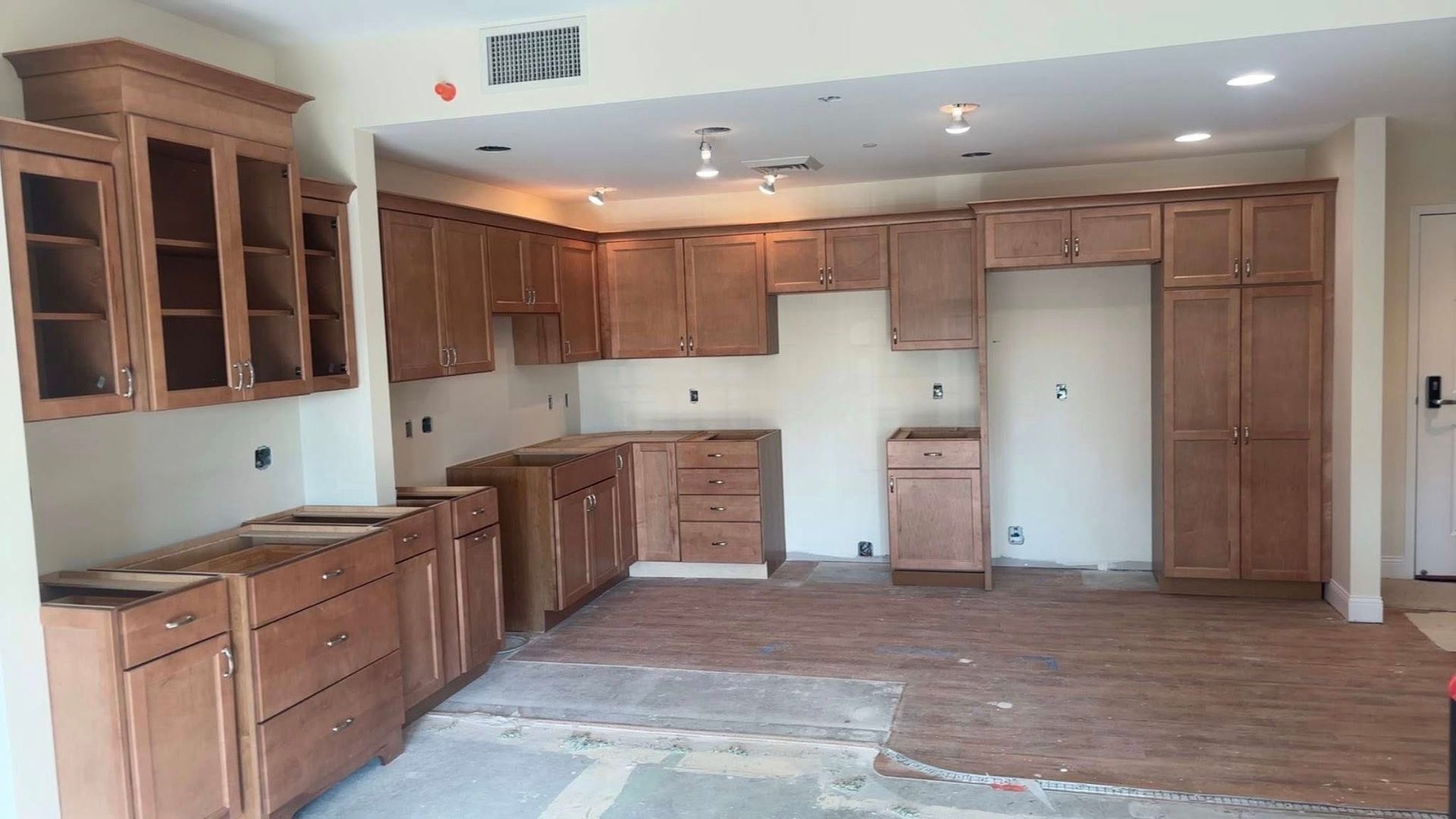 Empty kitchen with wood cabinets, white appliances, and a large rug on the floor