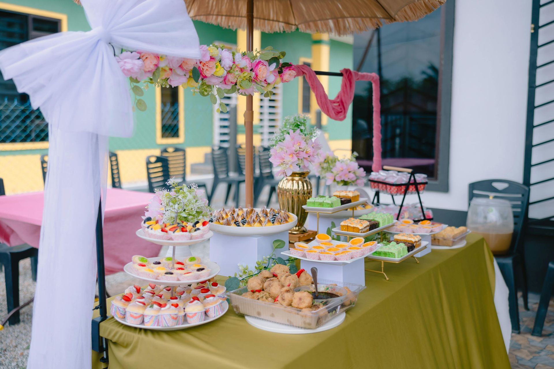 Decorated dessert buffet with cupcakes and pastries on a green table at an outdoor celebration