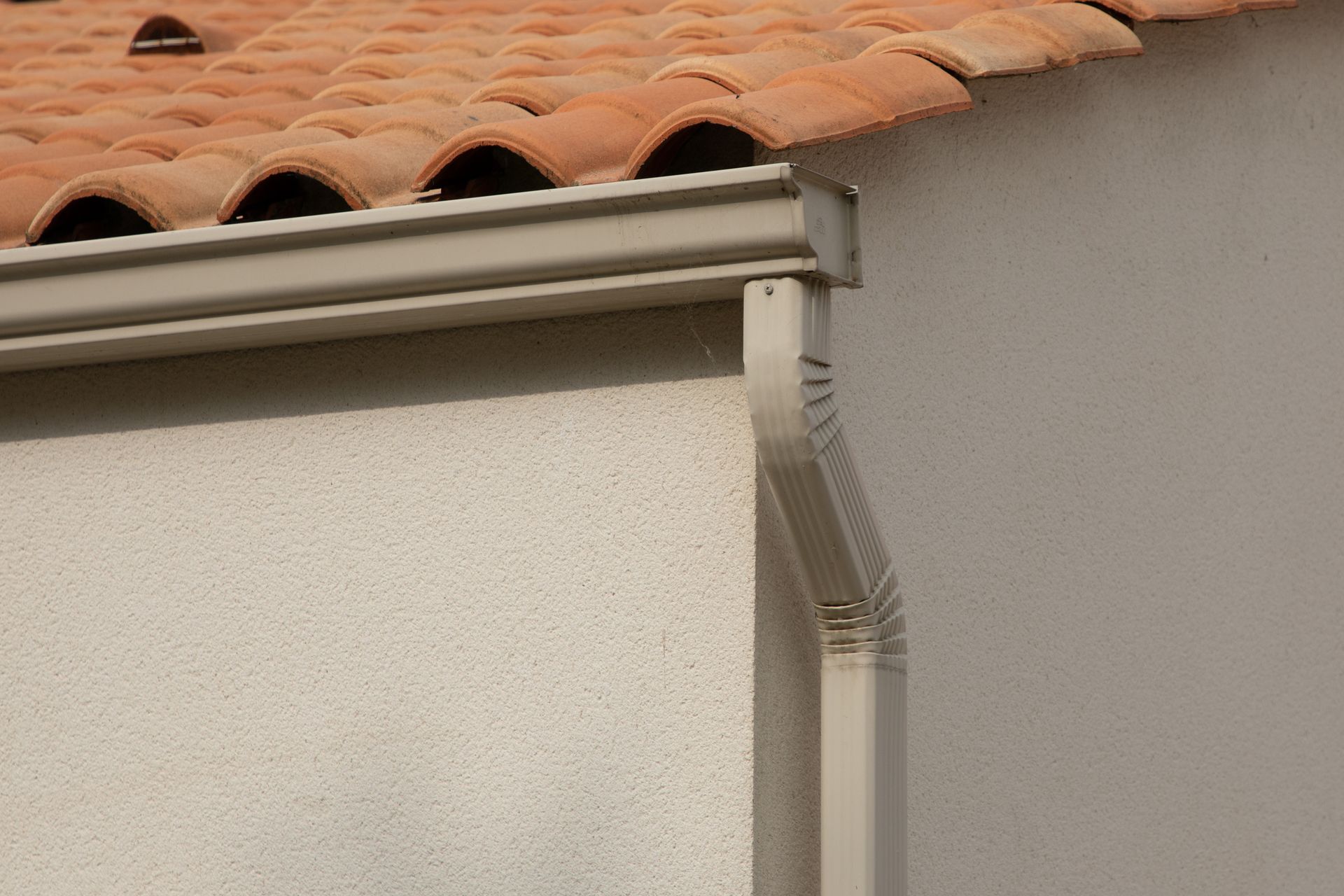 Seamless rain gutter installed on a modern sandy beige home corner roof. Seamless rain gutter installed on a modern sandy beige home corner roof.