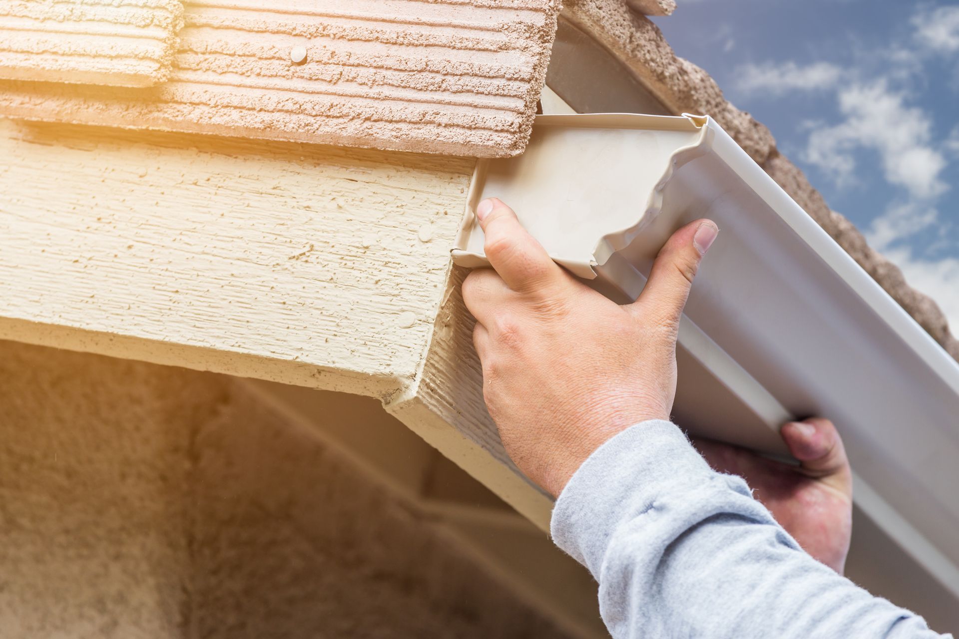 Male professional installing seamless rain gutter on residential home