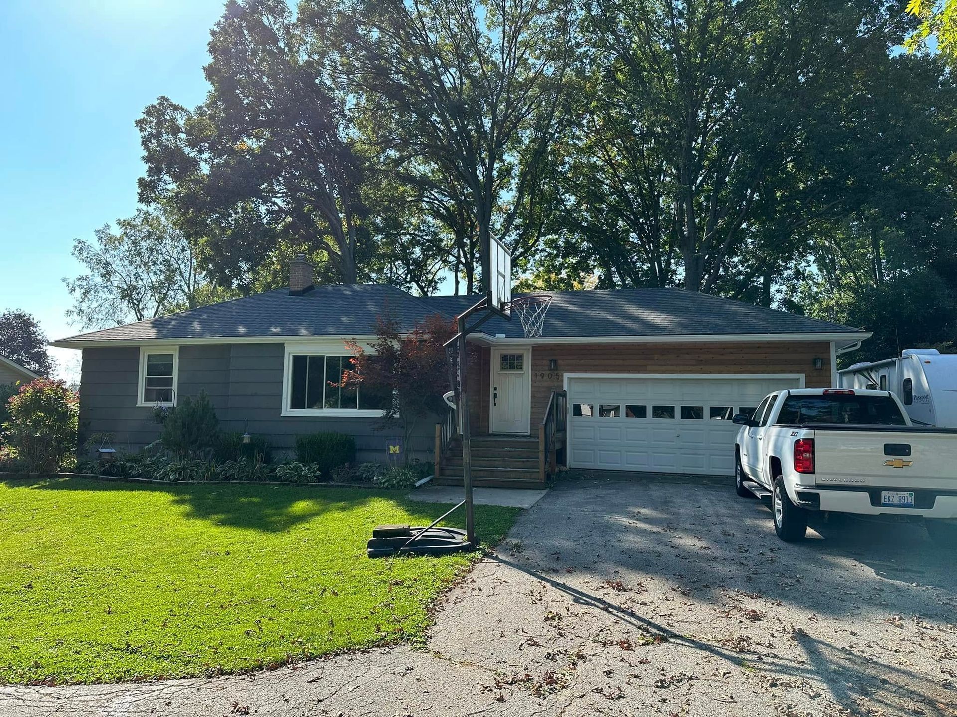 Single-story house with attached garage, green lawn, and white pickup truck in the driveway.