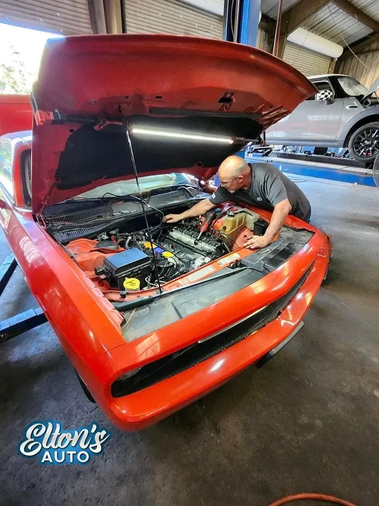 Robert working under hood of red car in our garage in Bloomingdale, GA | Elton's Auto