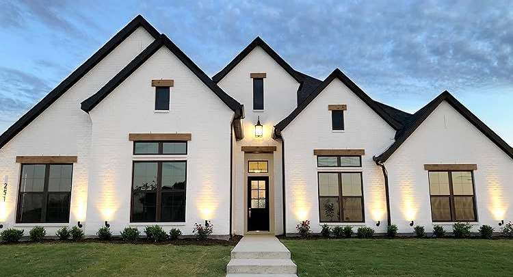 Modern white house with black trim, large windows, and a centered front walkway at dusk