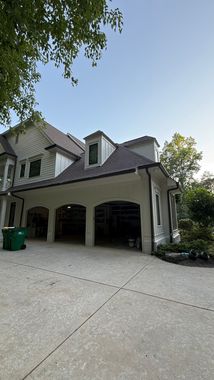 Large two-story house with a three-car garage and concrete driveway, viewed from the front yard.
