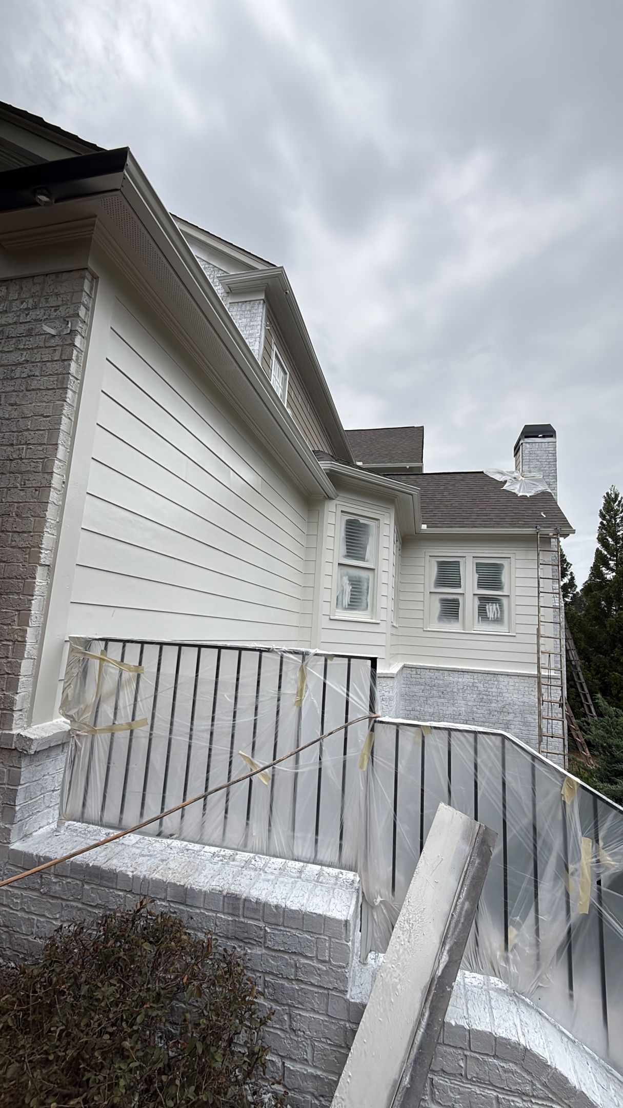 White house exterior with a curved ramp and porch railing under a cloudy sky