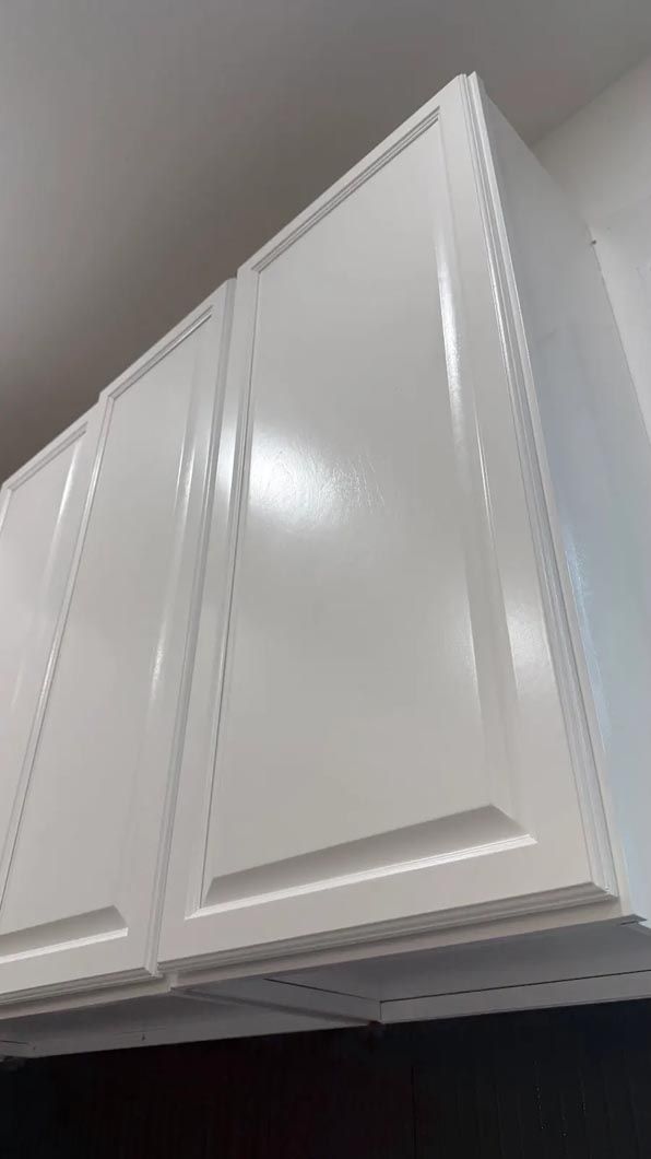 White kitchen cabinet doors viewed from below against a light wall and ceiling.