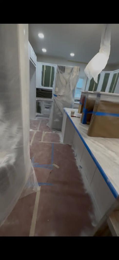 Narrow kitchen or utility hallway with white cabinets, red floor covering, and a large box on the counter
