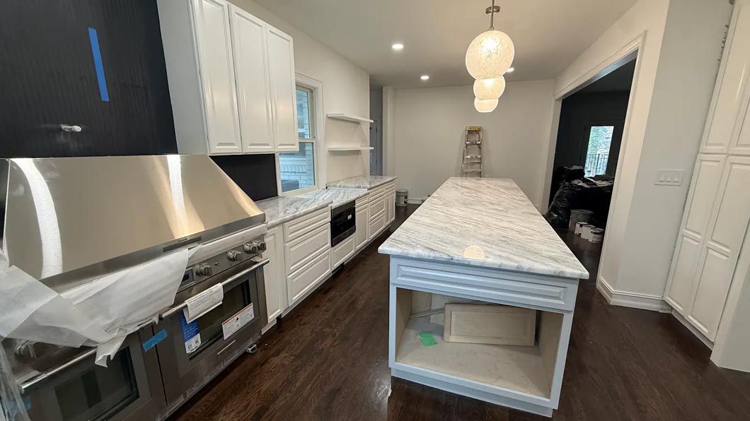 Bright modern kitchen with white cabinets, stainless range, island, and dark wood floors