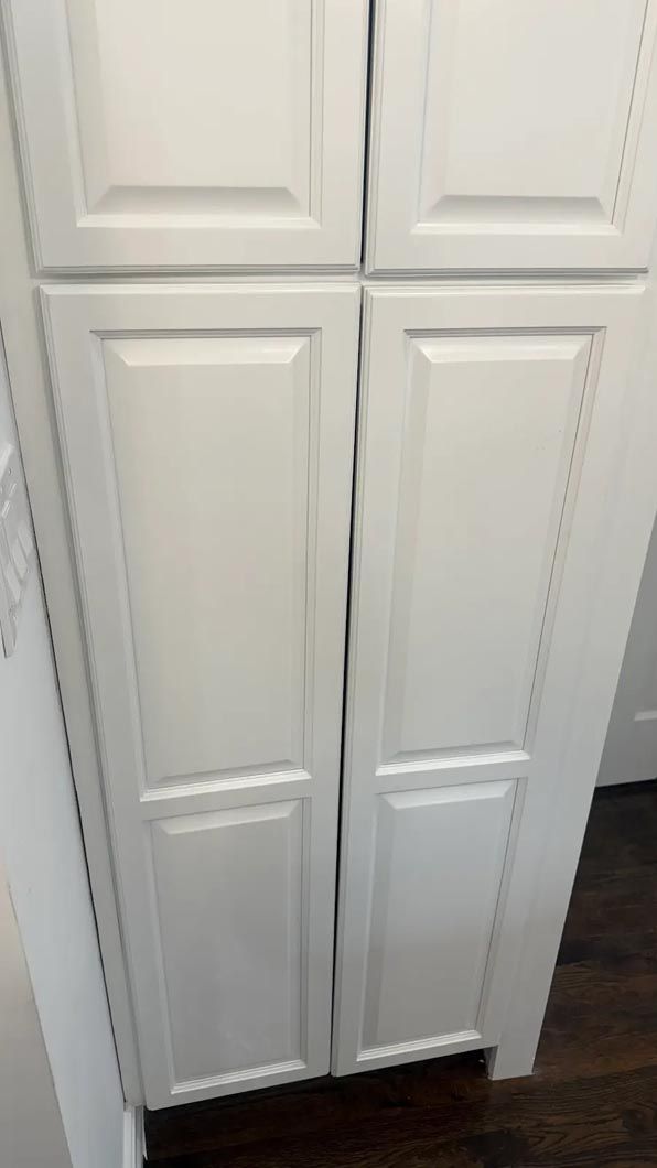 White double closet doors with paneled design in a room with dark wood flooring.