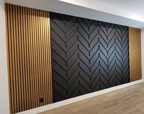 Modern interior wall with black chevron paneling flanked by vertical wood slats and light wood flooring