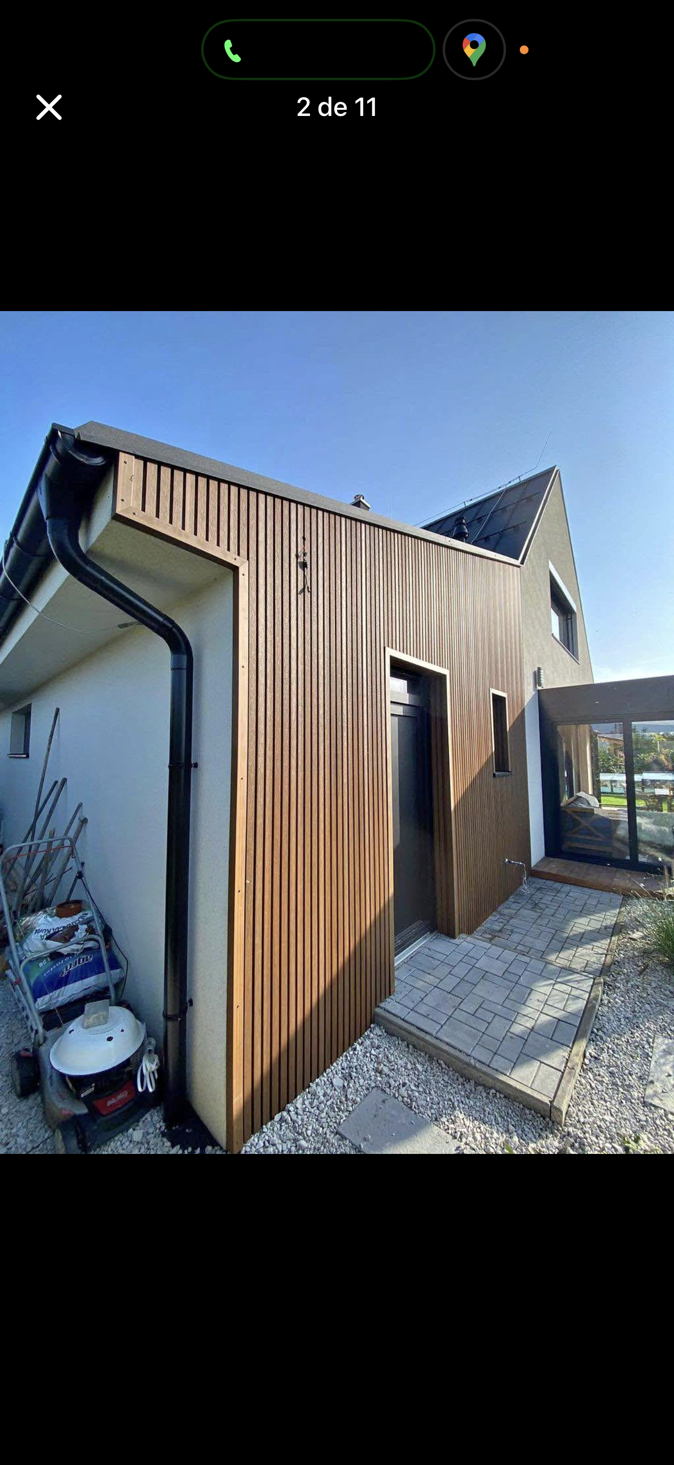 Modern wood-clad tiny house exterior with a small porch on gravel.