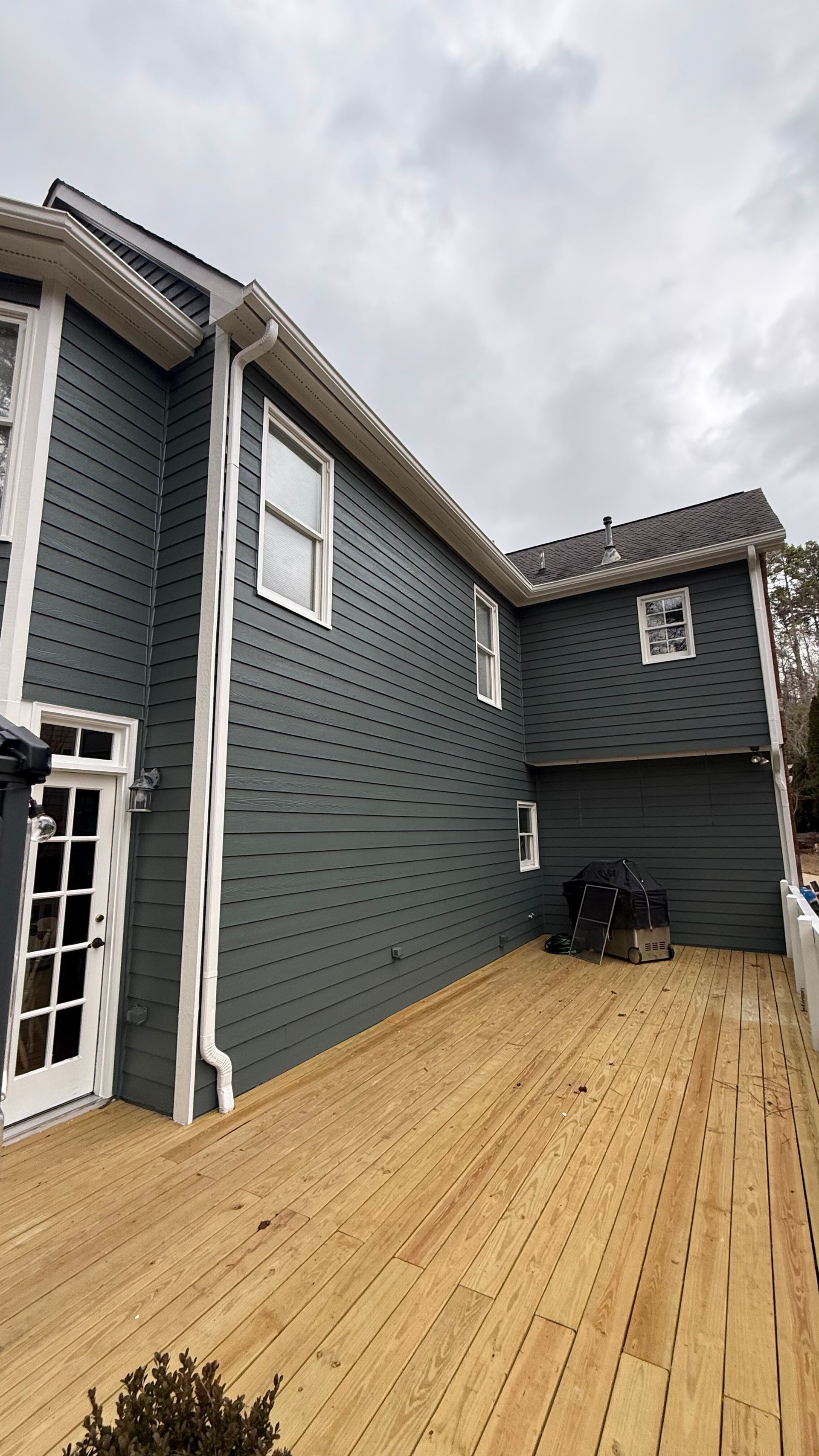 Gray-sided house with a wooden deck and cloudy sky overhead
