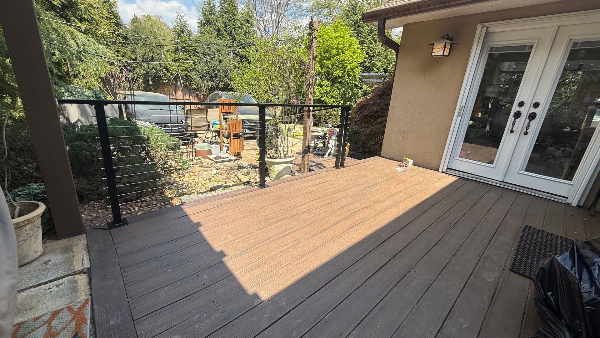 Wooden deck beside a house, with patio doors and a view of the backyard and trees.