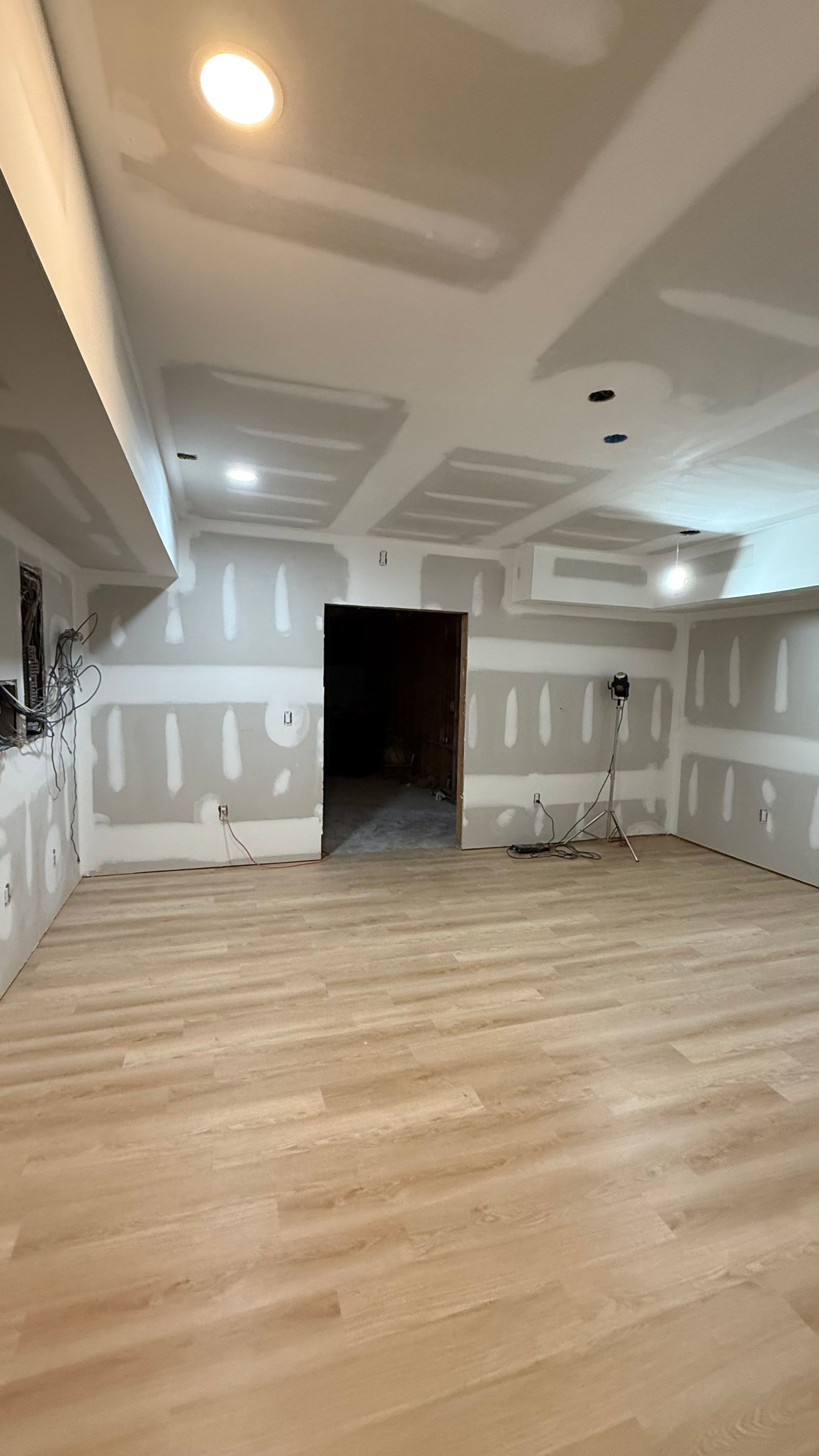 Empty unfinished room with taped drywall, wood floors, and recessed ceiling lights