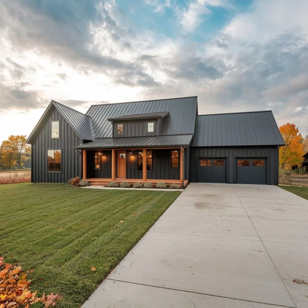 Modern dark-gray house with a metal roof, front porch, two-car garage, and a long concrete driveway at sunset
