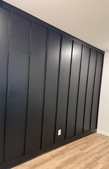 Dark matte built-in closet doors along a white wall with light wood flooring.