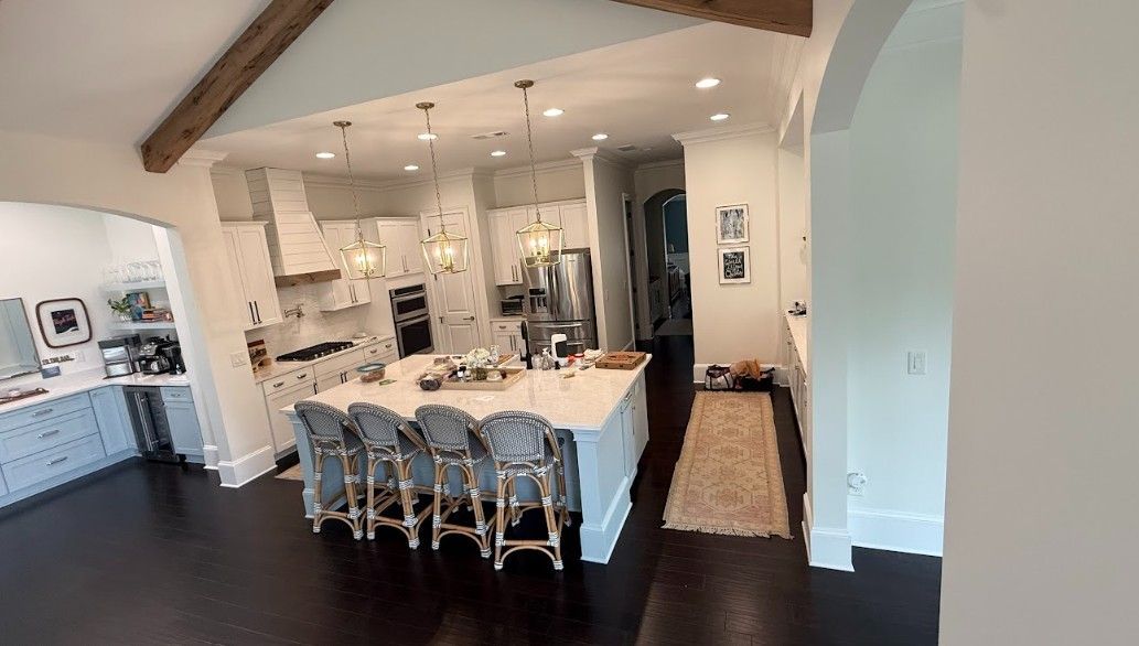 Modern open-concept kitchen and dining area with white cabinets, dark floors, and a large island with bar stools