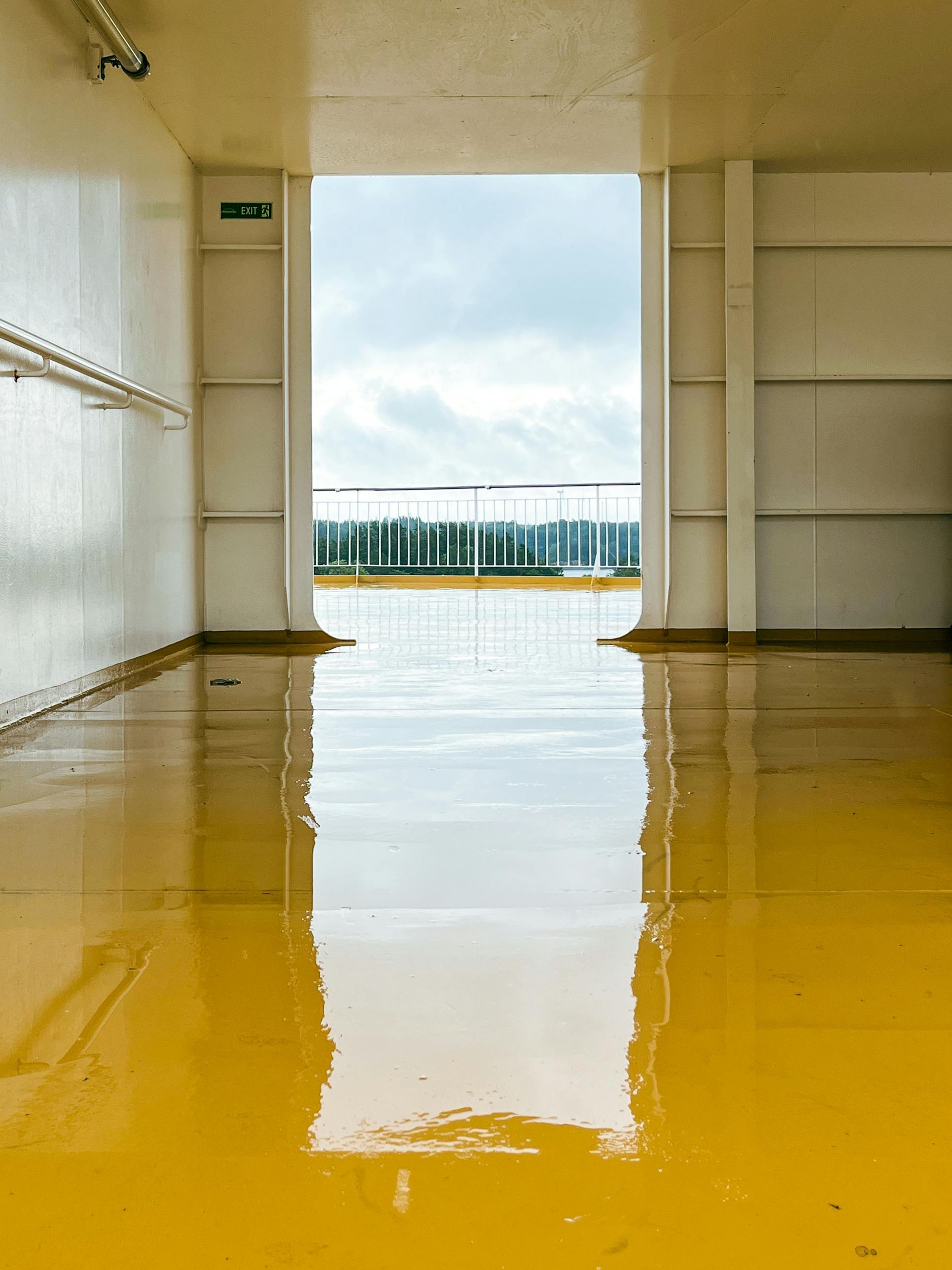 Flooded corridor with yellow water reflecting the doorway and distant view outside