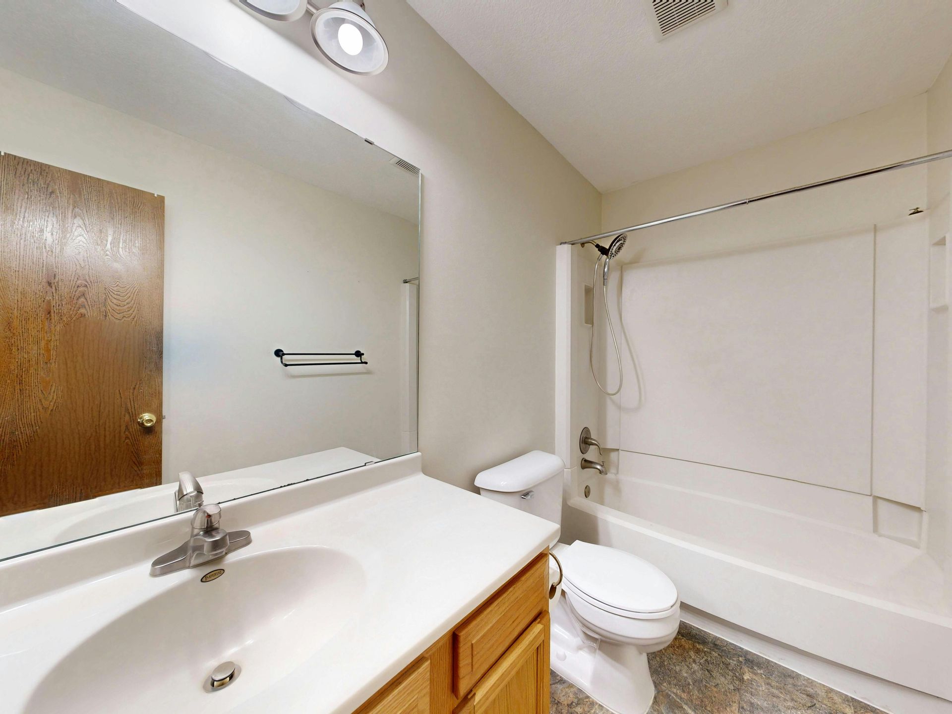 Bathroom with vanity mirror, sink, toilet, and a bathtub with shower curtain.