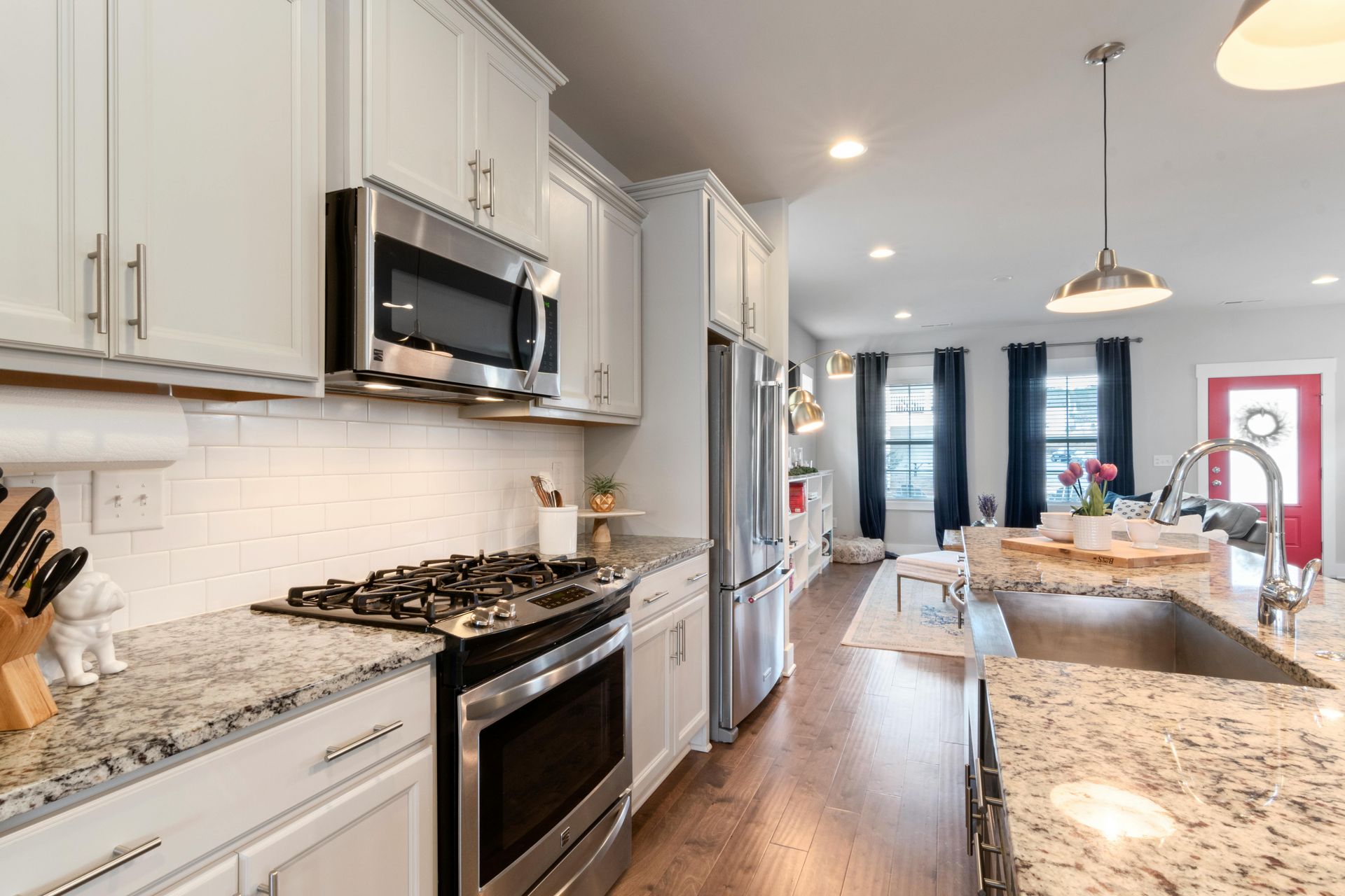 Bright modern kitchen with white cabinets, granite counters, stainless appliances, and a long island.