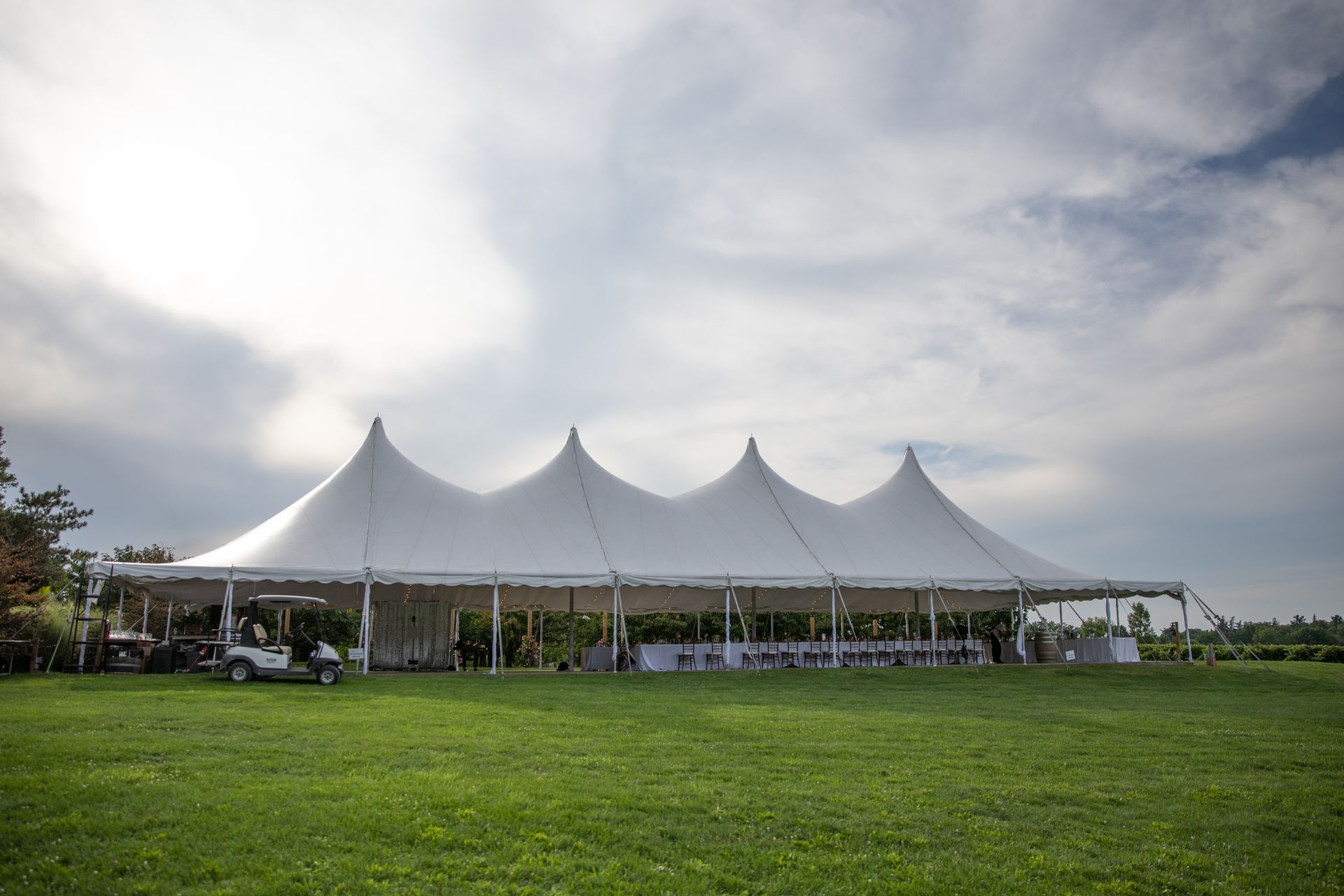 White event tent on a grassy field under a cloudy sky