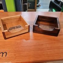 Two wooden branded display boxes on a wooden tabletop in a shop-like setting.