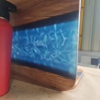 Blue abstract light panel with white streaks framed in wood, sitting on a tabletop