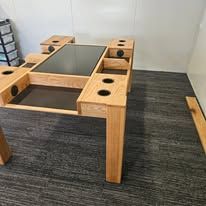 Wooden adjustable table frame with square cutouts, on a gray carpet in an empty room