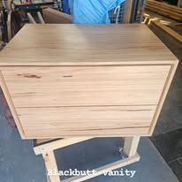 Light wood vanity cabinet with two drawers on a stand in a workshop setting