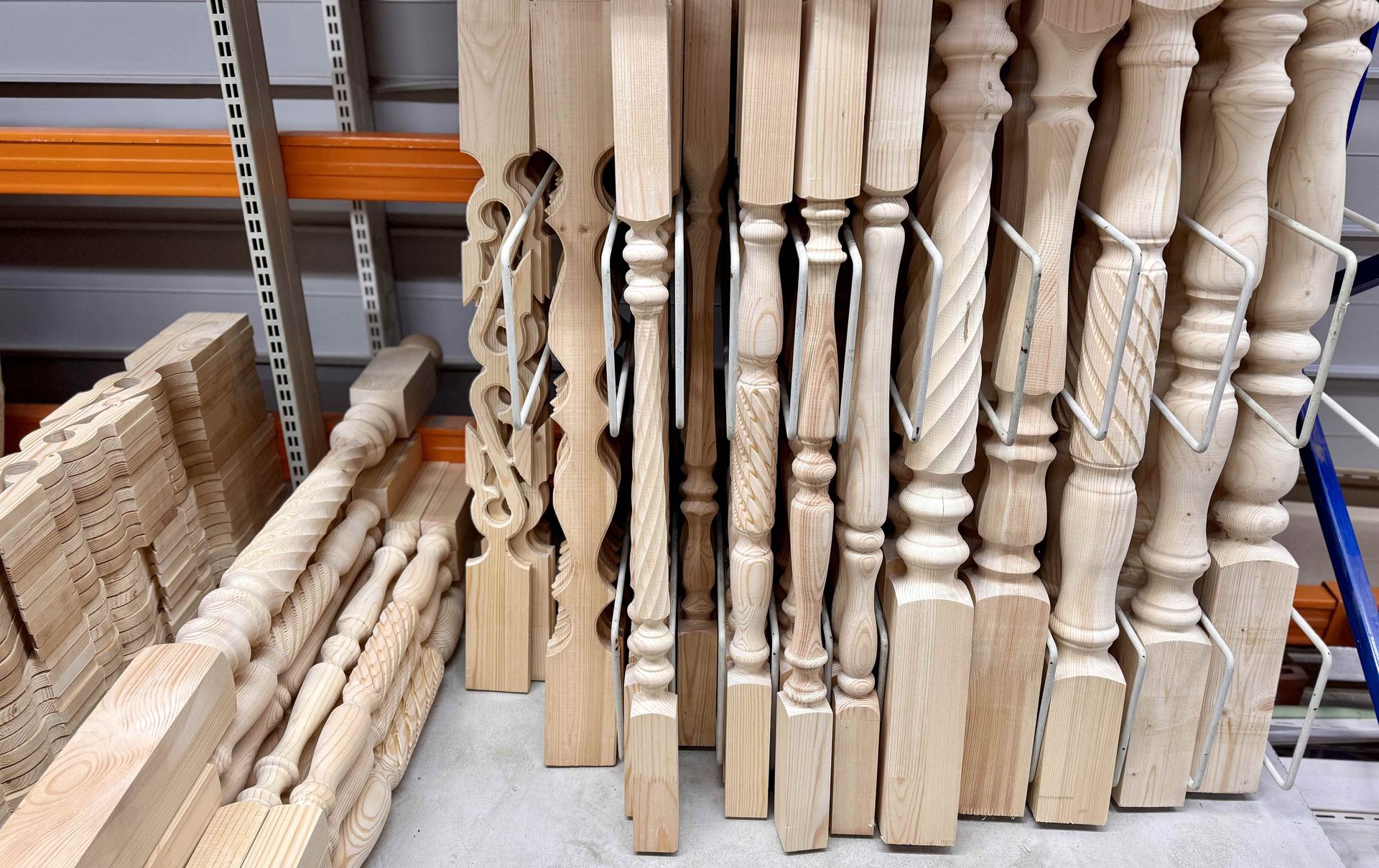 Stacks of unfinished wooden balusters and stair spindles stored on warehouse shelves.