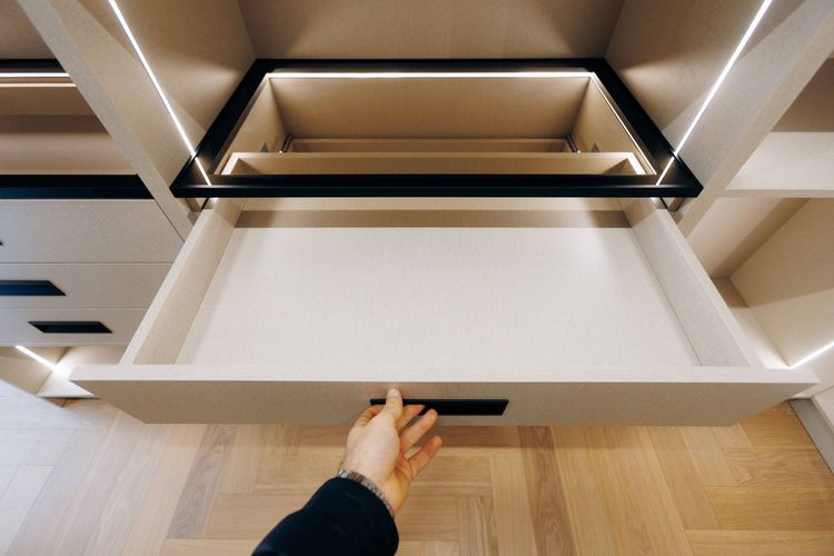 Hand opening a white kitchen drawer under a black cooktop in a modern kitchen