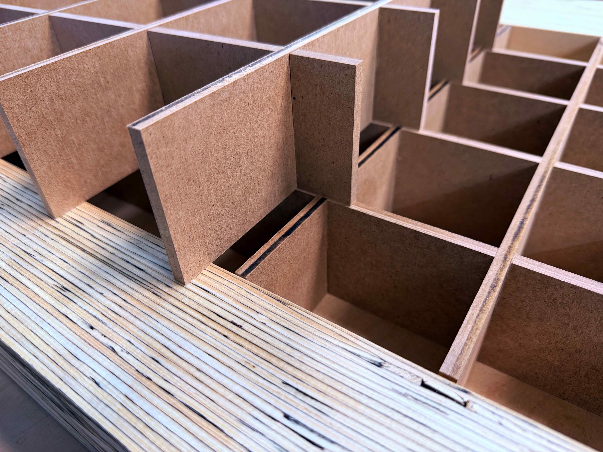 Cardboard compartments and dividers laid out in a workshop, viewed from above