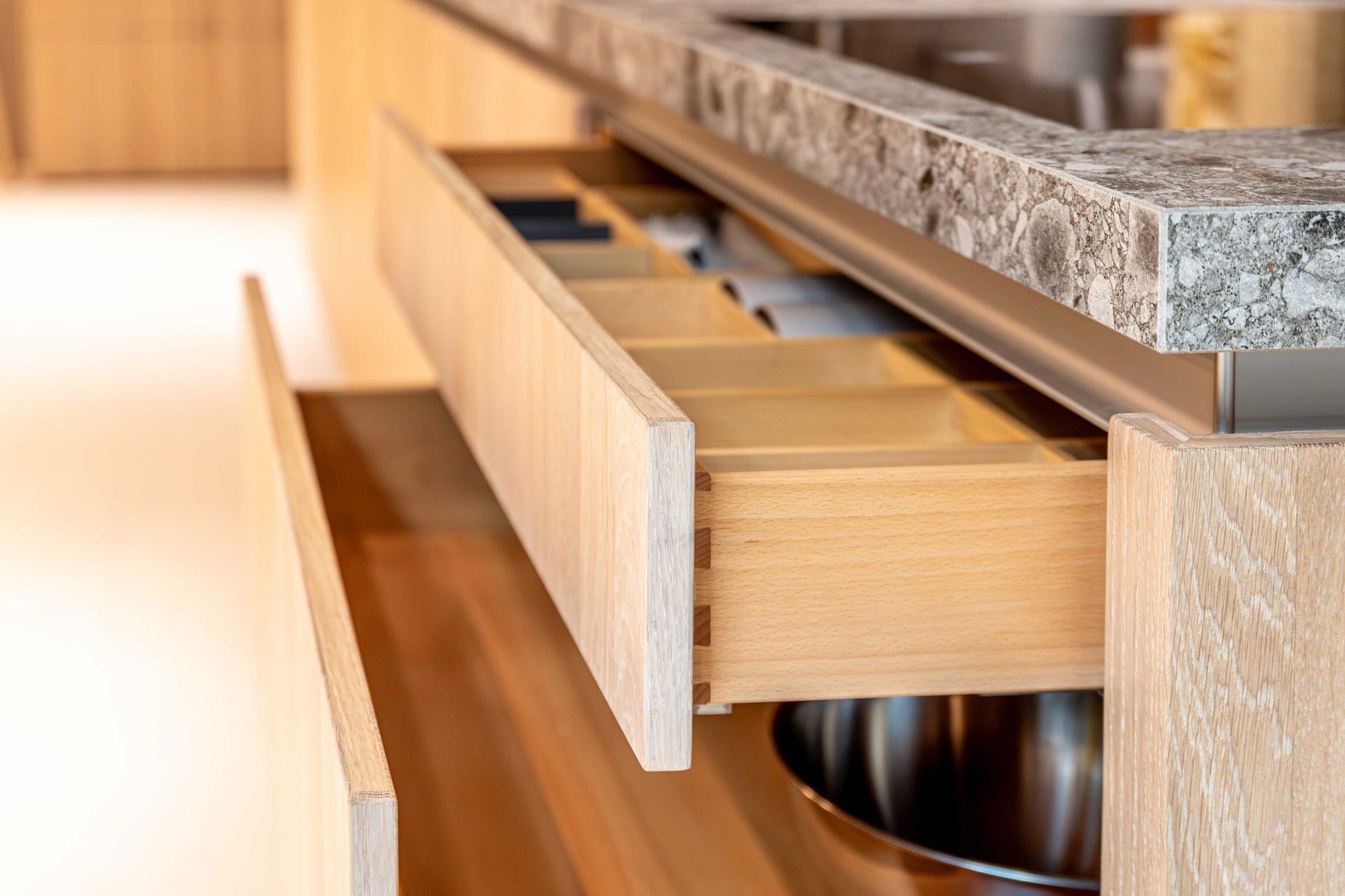 Open drawer in a modern kitchen cabinet with a stone countertop