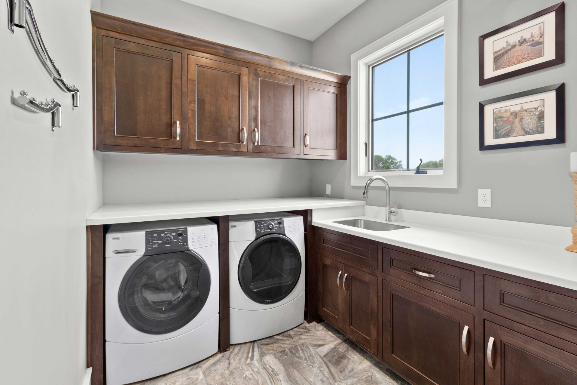 Laundry room with front-loading washer and dryer, wood cabinets, white counters, and a window