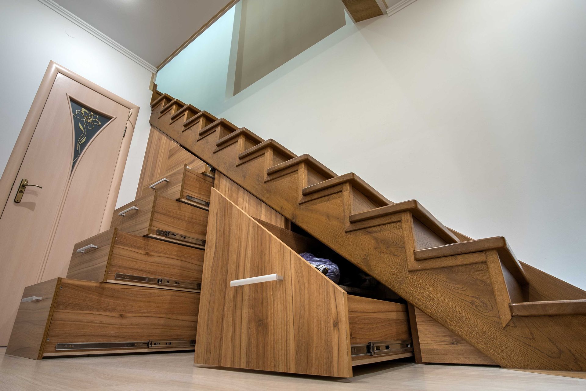 Under-stair wooden storage drawers and cabinets in a bright hallway