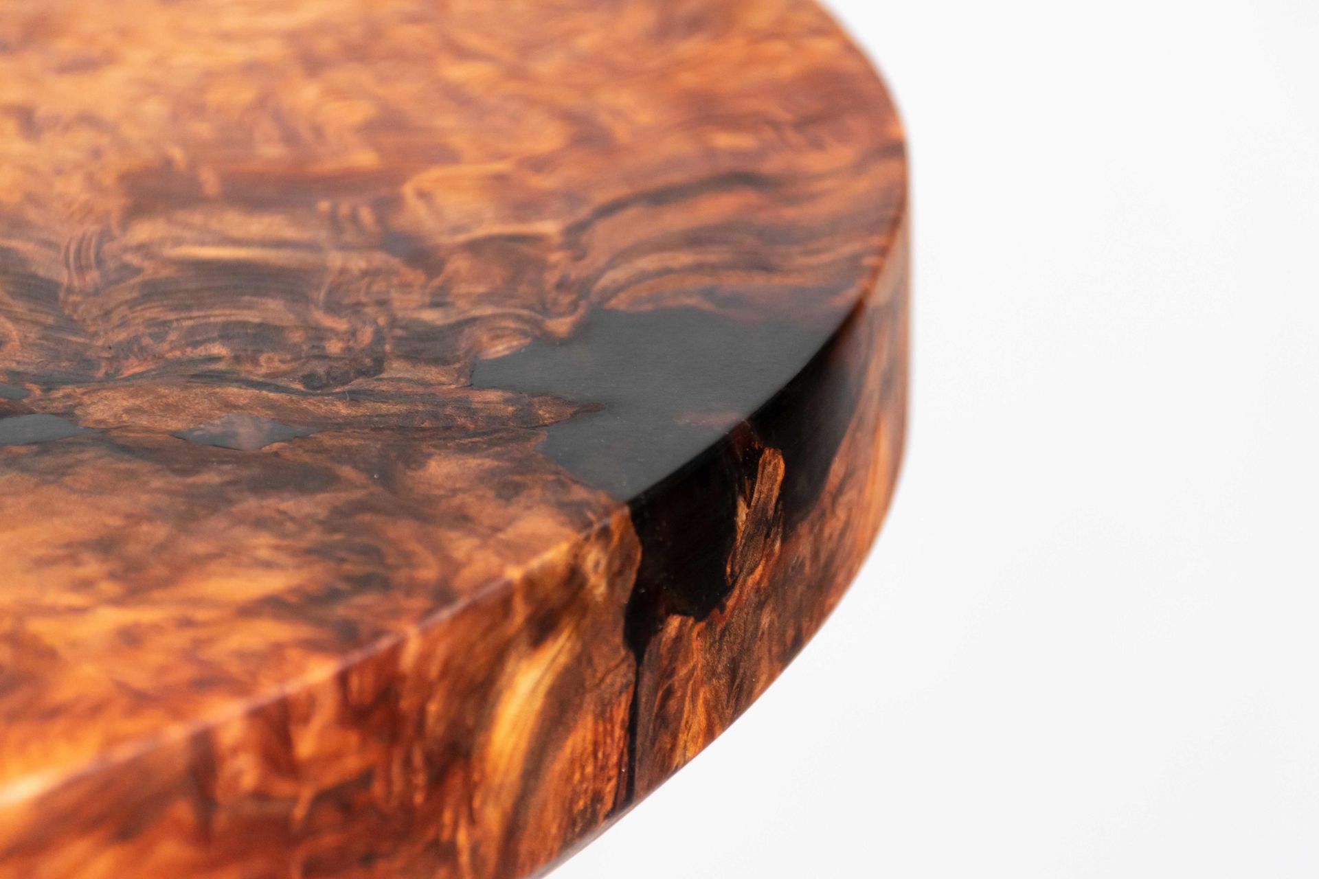 Close-up of a glossy, round wooden surface with rich brown grain and a white background