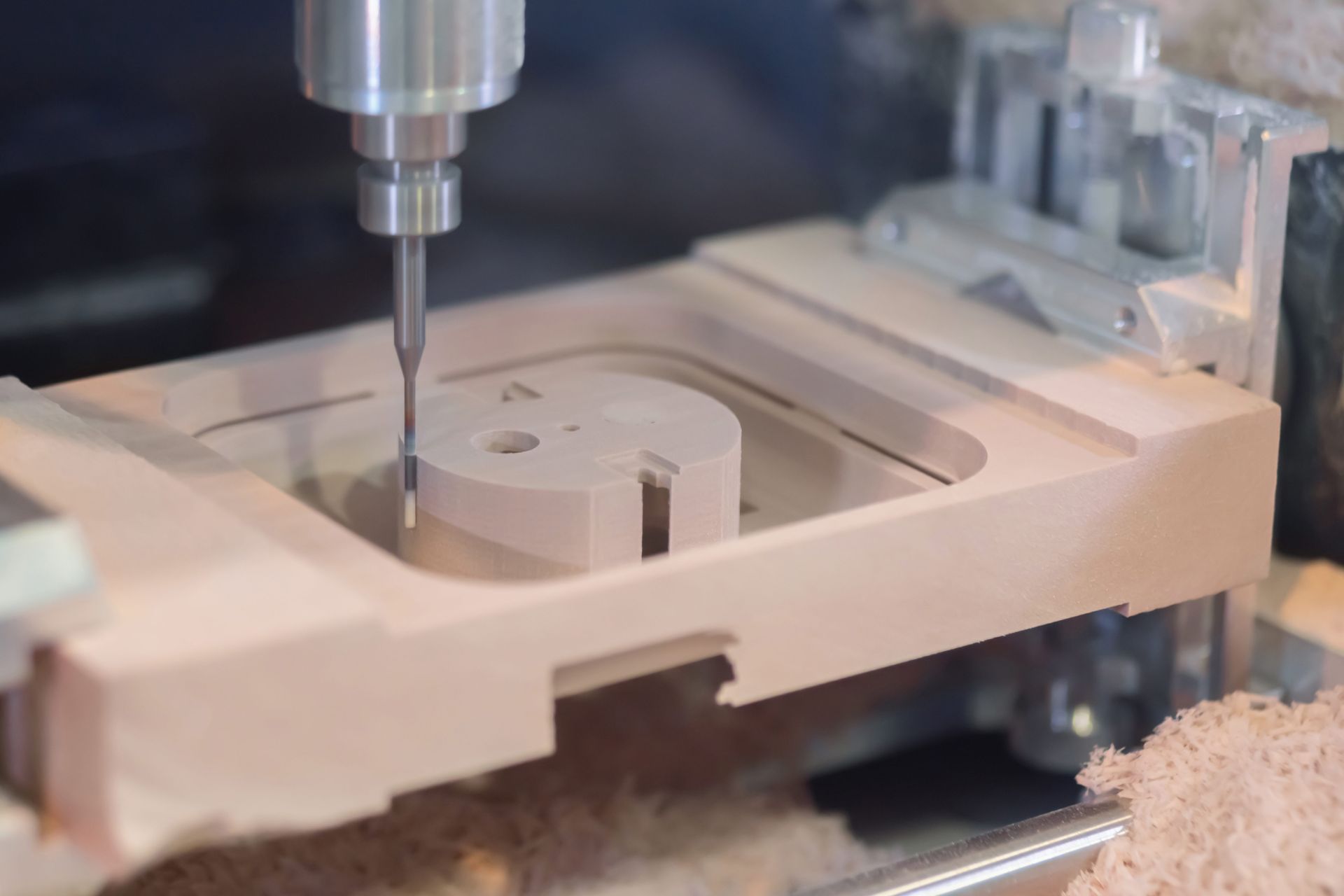 CNC machine milling a beige plastic part with a metal bit in a workshop