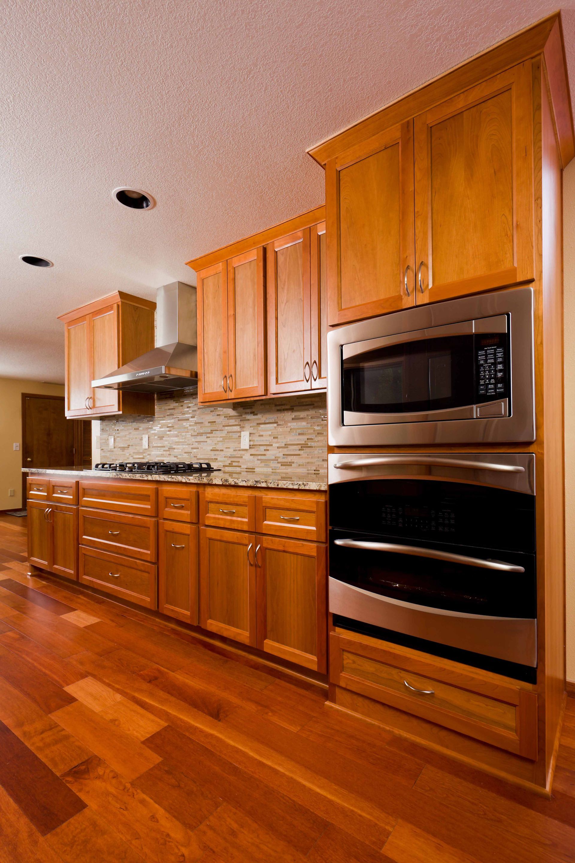 Modern kitchen with wooden cabinets, stainless steel appliances, and hardwood floors