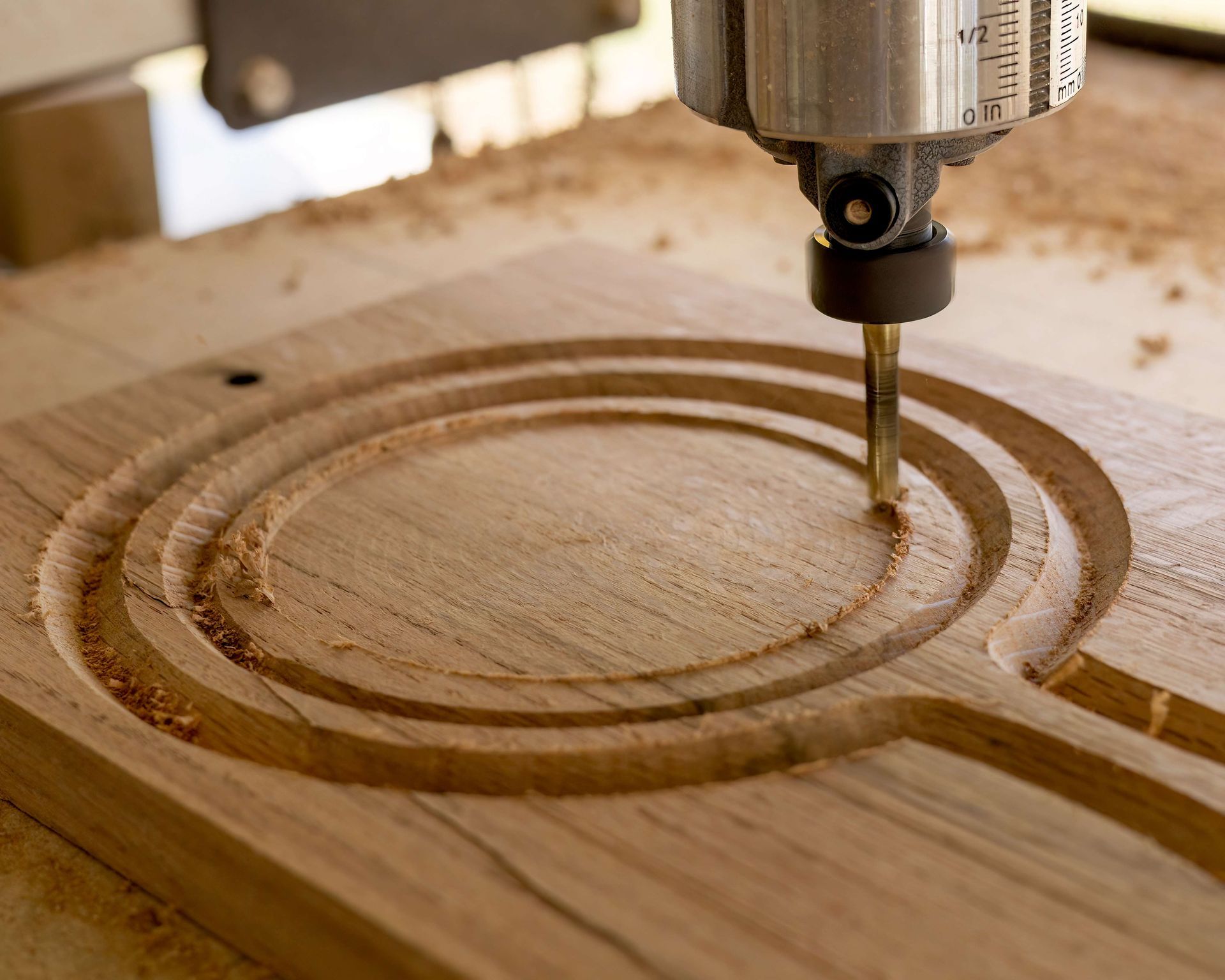 CNC router carving concentric circular grooves into a wooden board