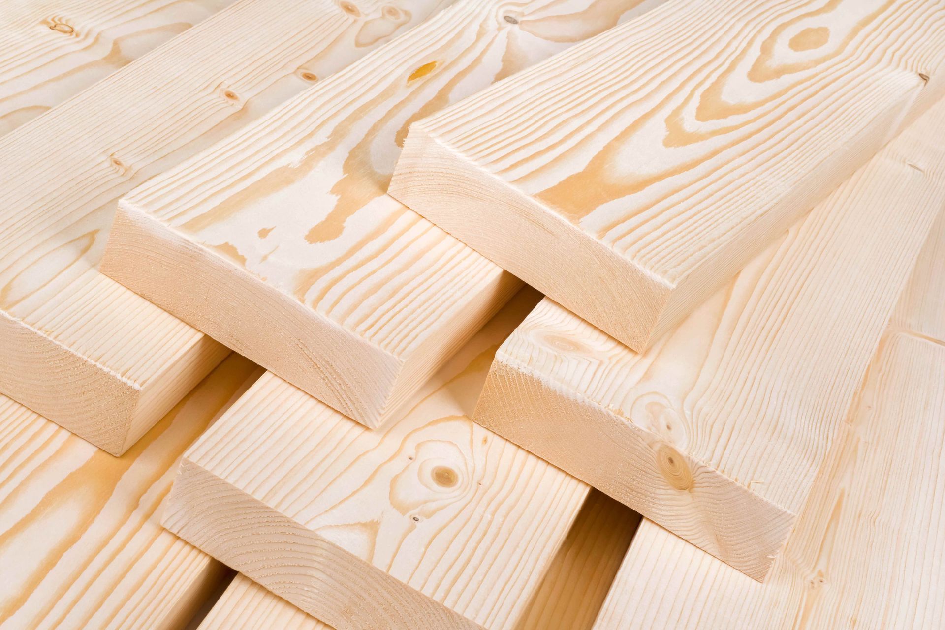 Stacked light pine lumber boards with visible wood grain and knots