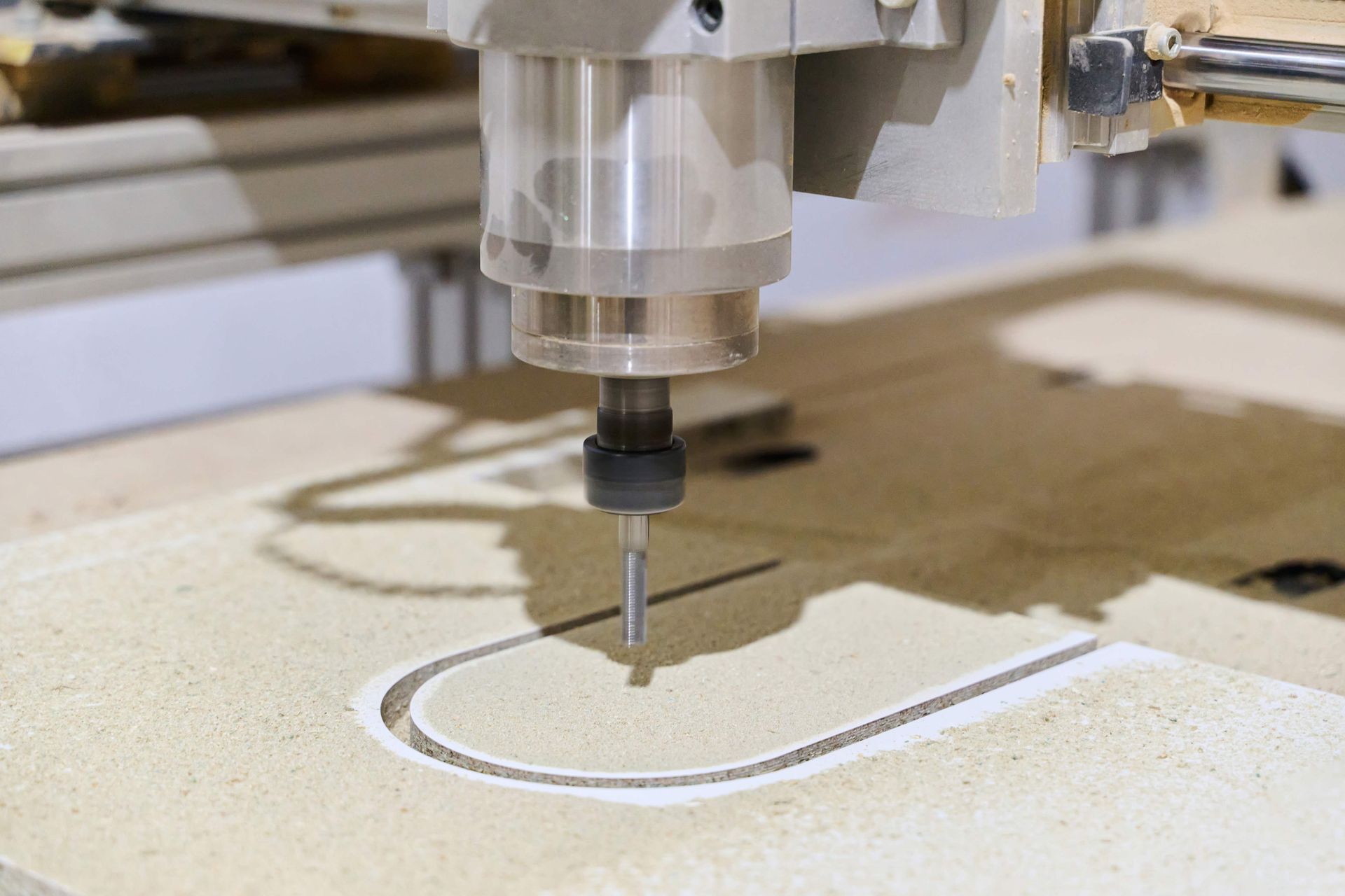 CNC router cutting a curved shape into wood on a workshop table