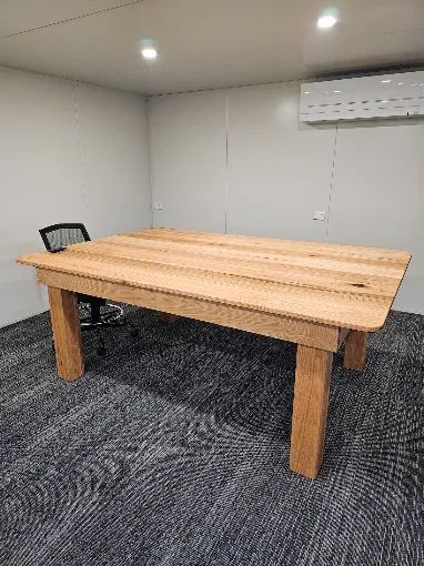 Small conference room with a wooden table, gray carpet, chairs, recessed lights, and a wall AC unit.