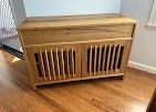 Wooden pet crate cabinet with slatted doors sitting on a hardwood floor by a wall