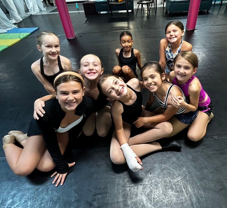 Group of smiling children in dancewear posing on a gym floor after class