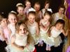 Group of children in ballet costumes smiling and posing together indoors