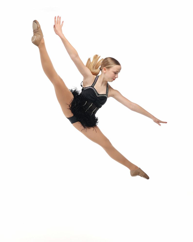 Ballerina in black leotard performing a high leap against a white background