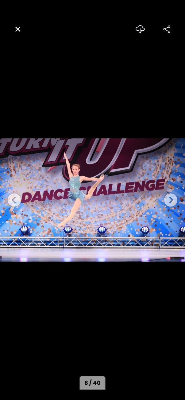 Dance competition stage with performers and a large “Dance Challenge” backdrop in blue and pink lights
