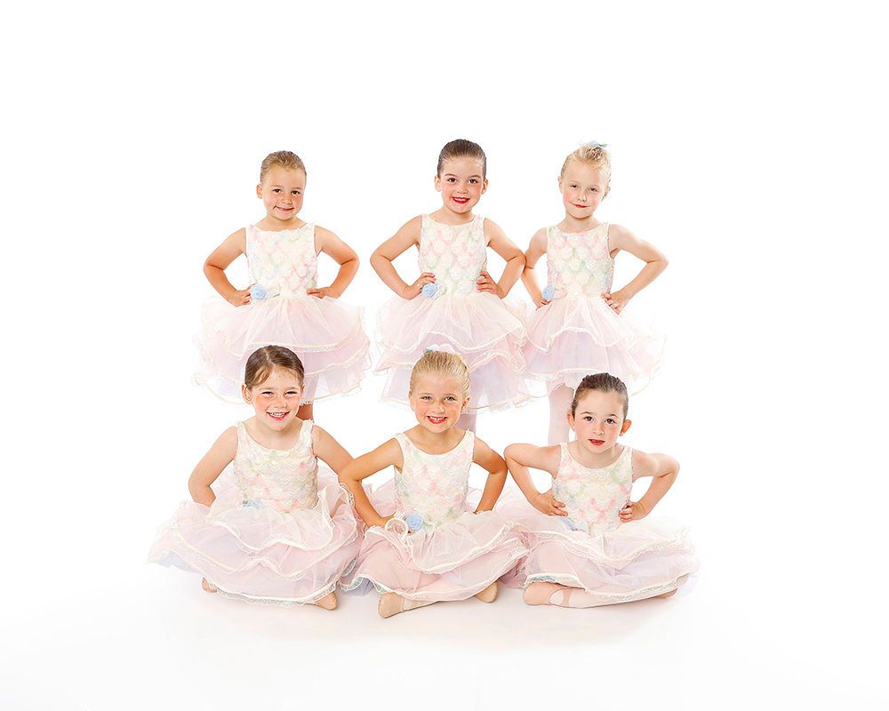 Six children in white ballet costumes posing on a white background.